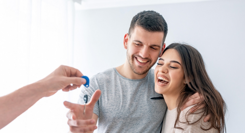 A realtor handing keys to a family of family